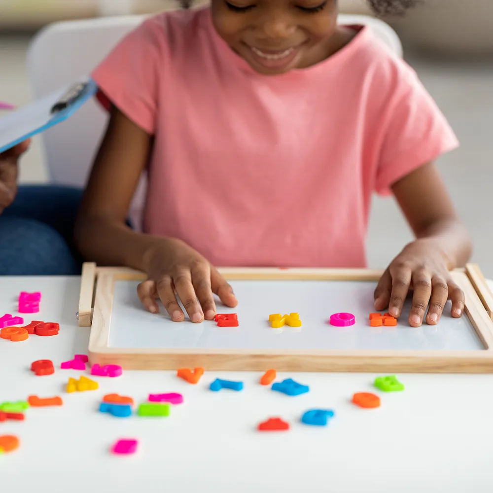 A child using magnetized colorful letters to spell HOME at a Bright Beginnings Academy daycare