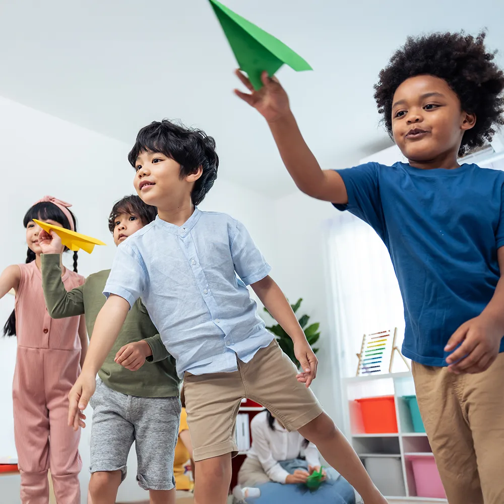Children launching colorful paper airplanes in a Bright Beginnings Academy daycare