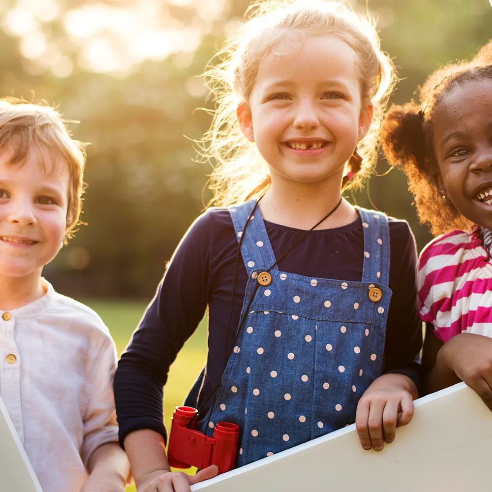 Three kids playing outside of Bright Beginnings Academy with binoculars