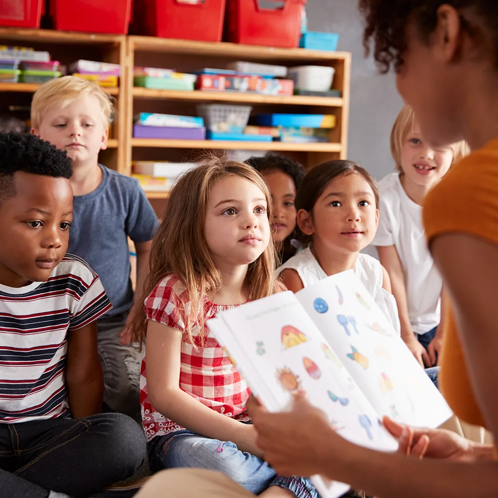 Children listening to a teacher read from a picture book at a Bright Beginnings Academy daycare