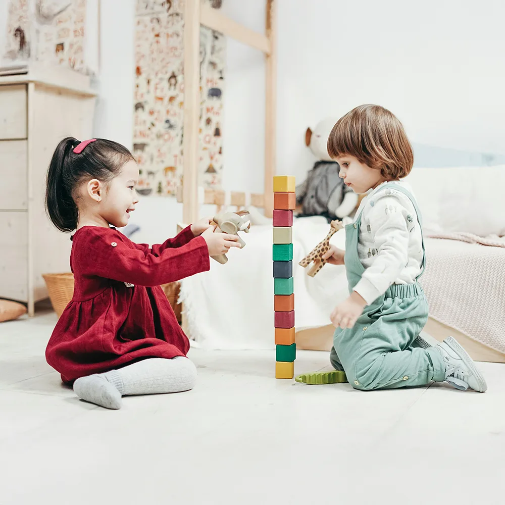 Two children stacking colorful blocks on a floor at Bright Beginnings Academy daycare