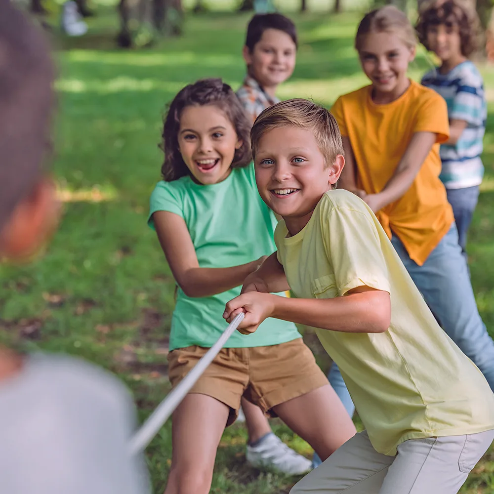 A group of children playing tug of war during summer camp at a Bright Beginnings Academy daycare