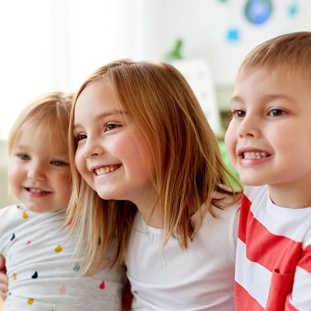 Three children hugging and smiling at a Bright Beginnings Academy daycare