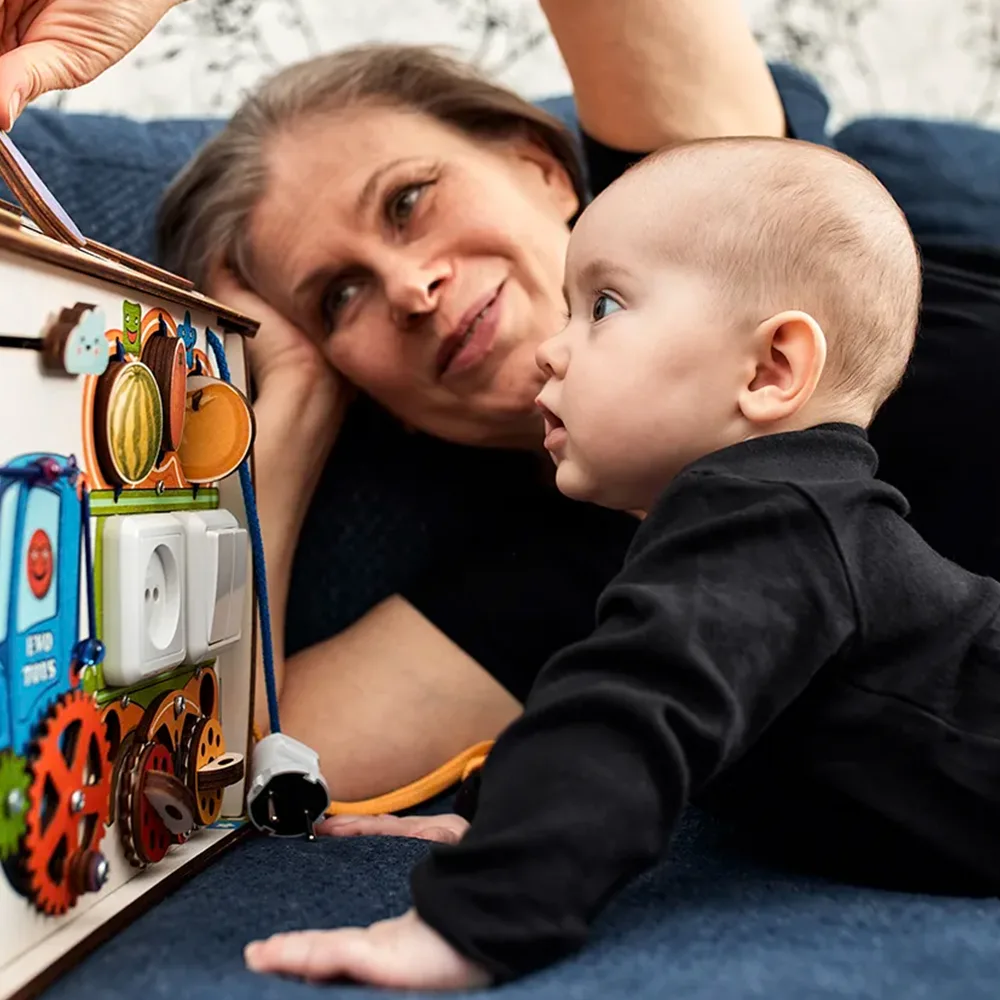 A teacher showing an infant a play box on the floor at a Bright Beginnings Academy daycare