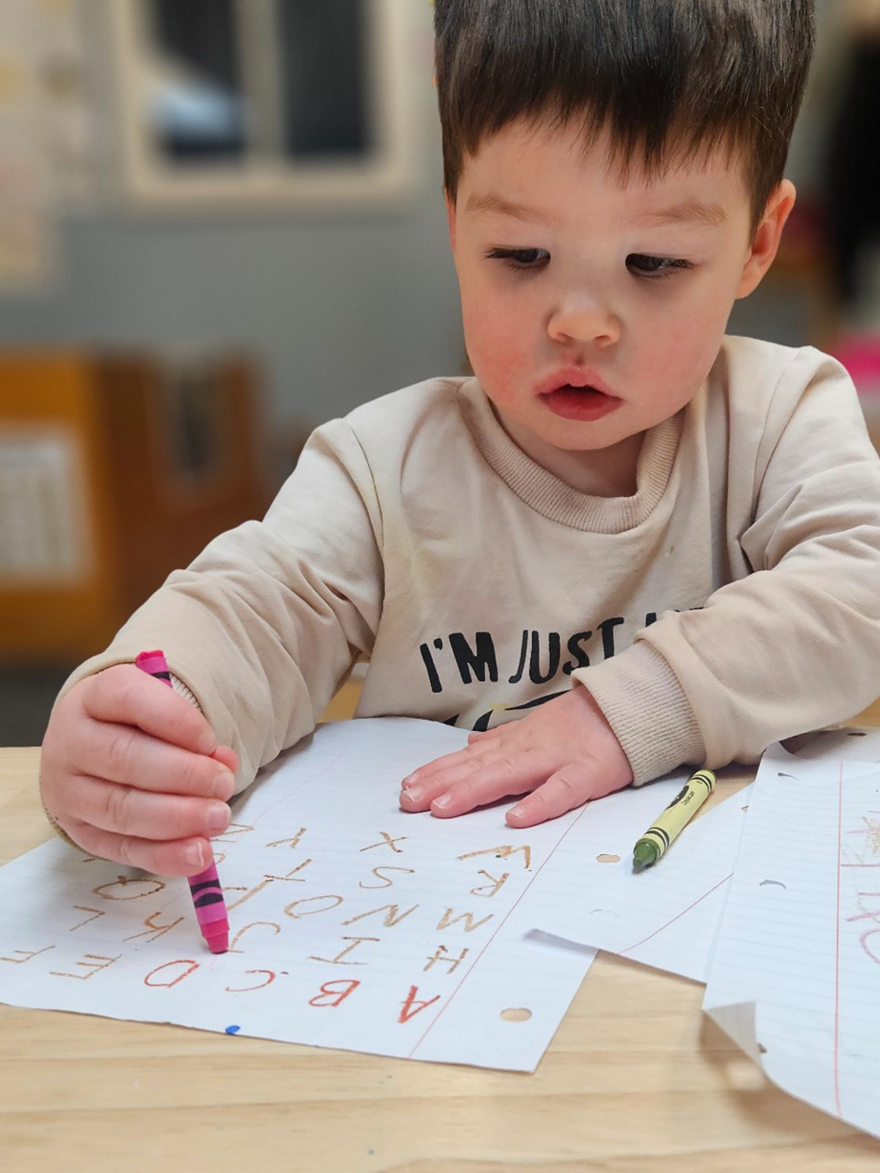 Child coloring the alphabet at a table at Bright Beginnings Academy daycare.