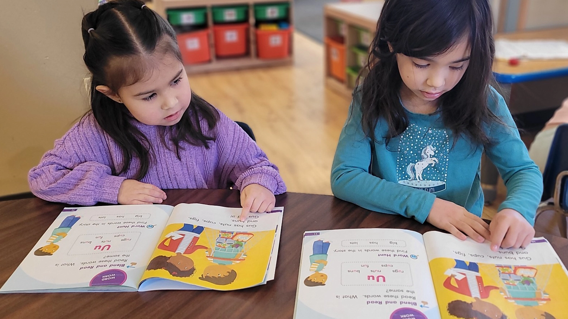 Two children reading books at a table