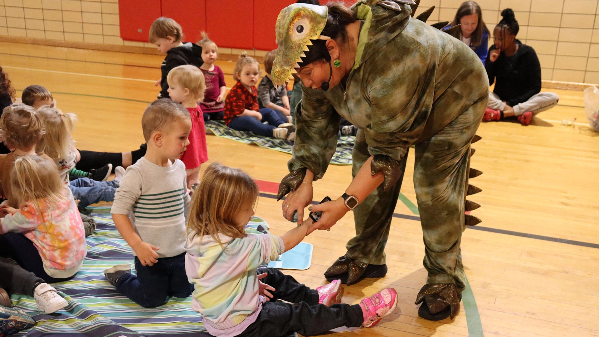 A teacher in a costume helping a child at Bright Beginnings Academy