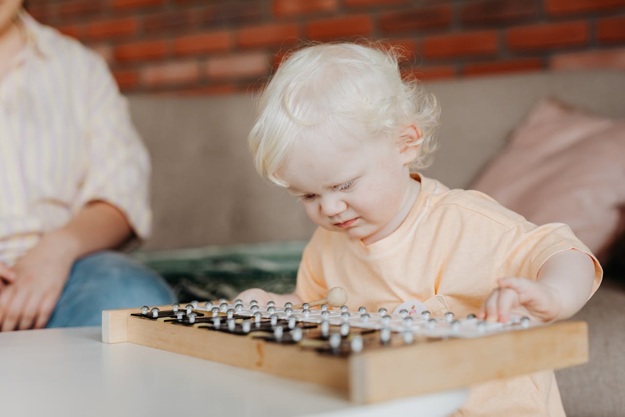 Baby in Orange Crew Neck Shirt Playing Xylophone